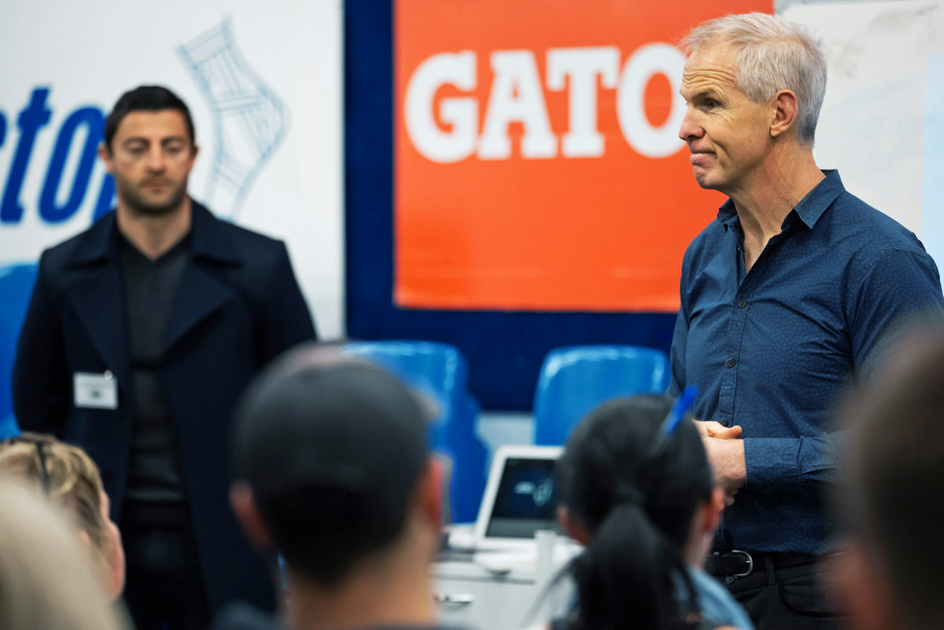 Matt Elliott presenting to a seated audience at an Allianz session, with teammate Mini in the background